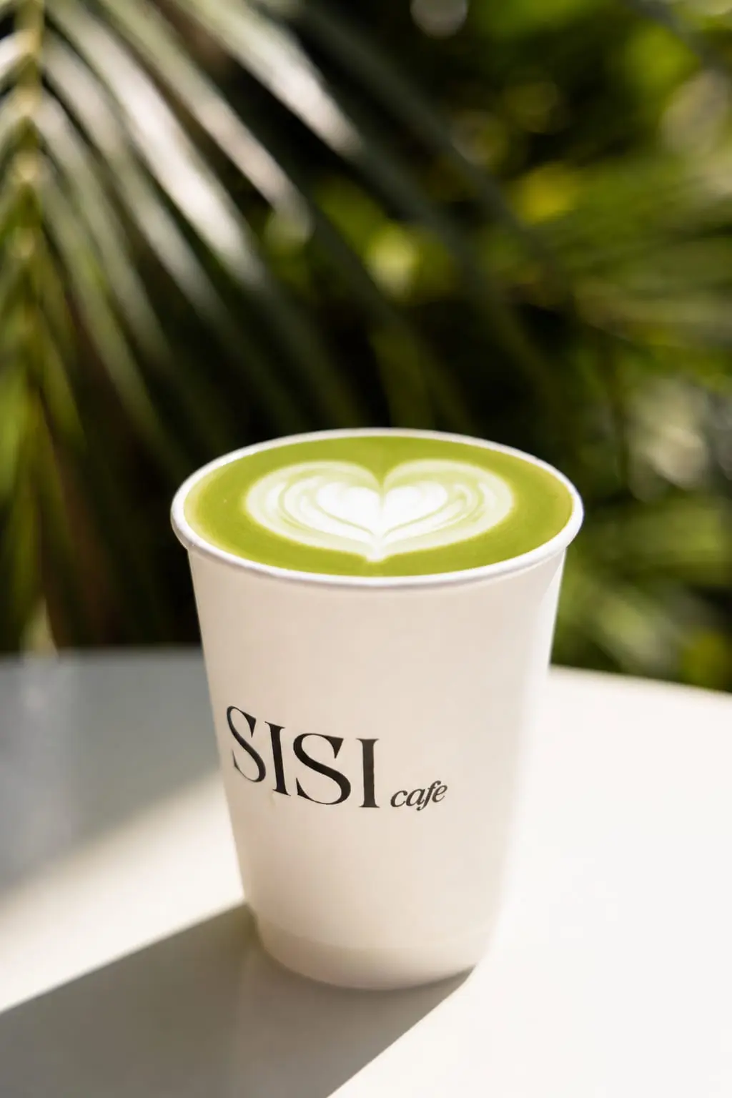 Matcha latte with leaf art in a SISI Cafe cup